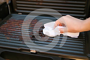 Dirty electric grill. Female hand wiping grill