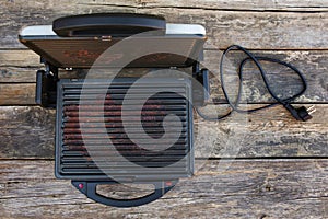 Dirty electric grill on old wooden background