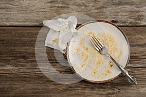 A dirty empty plate on wooden table after dinner