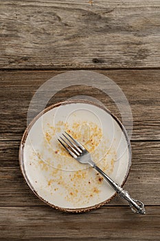 A dirty empty plate on wooden table after dinner