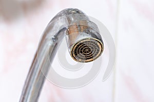 Dirty faucet aerator with limescale, calcified water tap with lime scale in kitchen, close up photo