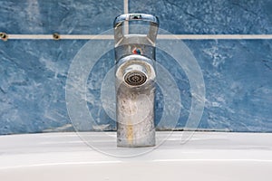 Dirty faucet with limescale, calcified water tap with lime scale on washbowl in bathroom