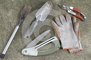 Dirty Gardening tools, shovel, gloves, pruning shears and saw