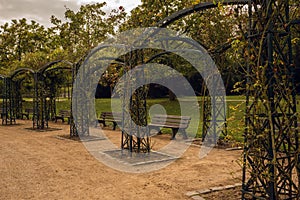 Dirty gravel road with  benches and arches in a park in autumn with yellow, green and red trees