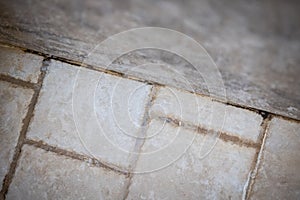 Dirty grout with beige tiles in a bathroom with mold, rust and soap residue.