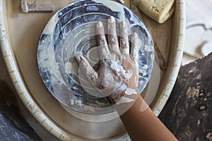 Dirty hand of potter in white clay on potter`s wheel