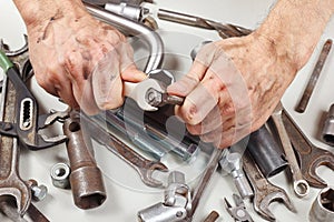 Dirty hand of repairman with wrench to tighten the nut