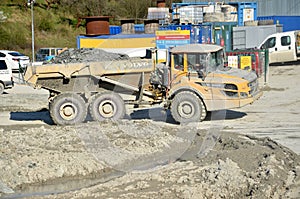 Dirty heavy Volvo dumper loaded by rock moving in work site.