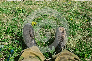 Dirty hiking boots on the grass during a halt during a hike