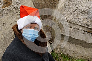 Dirty homeless woman in a medical mask and a Santa Claus hat