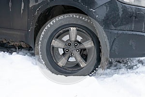 Dirty icy car wheel on a snowy background