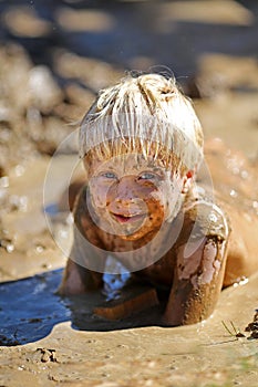 Dirty Little Child Laying in A Wet Mud Puddle