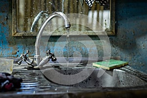 Dirty little wash basin for hands. rusty water flows from the tap.