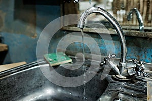 Dirty little wash basin for hands. rusty water flows from the tap.