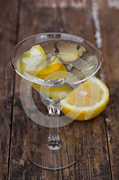 Dirty martini chilled and garnished with a lemon twist on wooden table