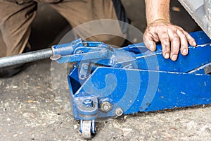 Dirty mechanic hands with blue car jacklift elevator