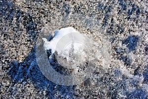 Dirty melting snow with clean white spot in center, early spring, natural background, close up