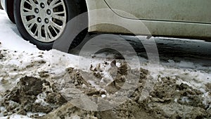 Dirty messy snow near car wheel. Mud  salt and chemicals on road in winter. Ecology problem in city.