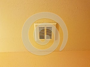Dirty metal bathroom vent on orange or yellow ceiling