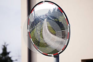 A dirty mirror stands at a bend in the road in a mountain village to help visibility in traffic or prevent accidents. in the