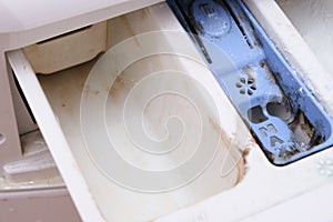 Dirty moldy washing machine detergent and fabric conditioner dispenser drawer compartment close up. Mold, rust and limescale in