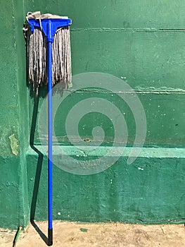 Dirty mop leaning against the green wall