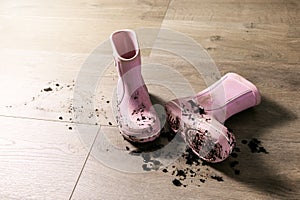 Dirty muddy kids rubber rain boots on laminate floor