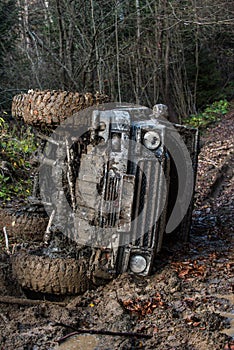 Dirty offroad car with dark forest on background.