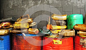 Dirty & oily plastic canisters on waste oil barrels tank