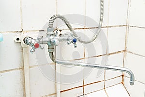 Dirty old faucet with limescale or lime scale on it, dirty calcified and rusty shower mixer tap and hose, moldy tiles on