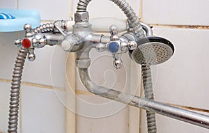 Dirty old faucet with limescale or lime scale on it, dirty calcified and rusty shower mixer tap and hose, moldy tiles on