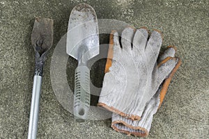 Dirty and old garden shovels and gloves on concrete floor.