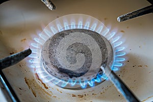 Dirty old kitchen gas burner.Fragment of a gas stove, bright blue flame