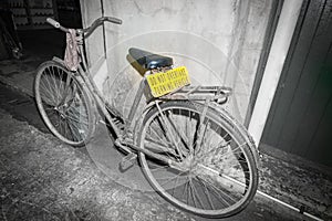 Dirty old pushbike leaning against wall in back street with brig