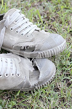 Dirty old shoes on grass background, still life style