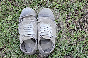 Dirty old shoes on grass background, still life style