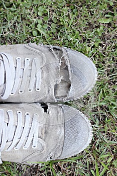 Dirty old shoes on grass background, still life style