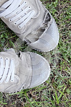 Dirty old shoes on grass background, still life style