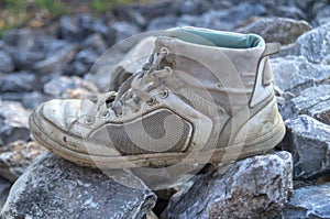 Dirty old shoes on rock in sunny day