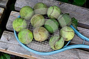 Dirty old tennis balls and vintage tennis racket on wooden bench. Close-up, top view. Leisure, activity, outdoor games