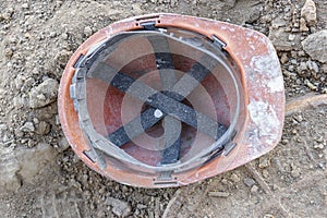 Dirty old work helmet left on the ground of construction site