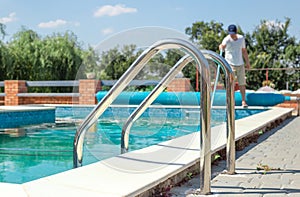 Dirty outdoor pool. Cleaner of swimming pool. Man cleaning outdoor swimming pool with vacuum tube cleaner in summer. Seasonal