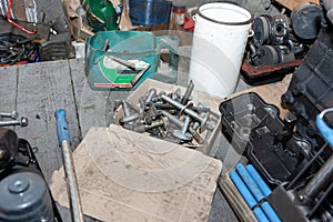 A dirty pile of bolts lies in a cardboard box on the floor