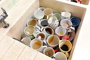 Dirty pile of unwashed cups and mugs in wash basin