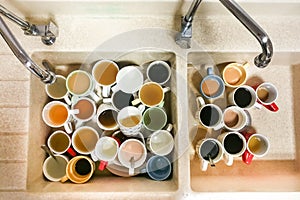 Dirty pile of unwashed cups and mugs in wash basin