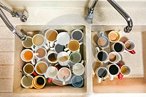 Dirty pile of unwashed cups and mugs in wash basin photo