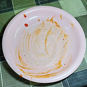 a dirty pink plactic plate with chilli sauce and ketchup spot