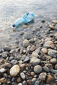 Water pollution. Plastic bottle on the river beach.