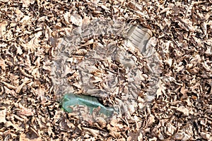 A dirty plastic and glass bottle left in the autumn forest.