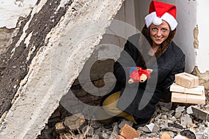 A dirty poor homeless woman in a New Year`s hat with a smile holds gifts in her hands